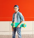 Portrait stylish teenager boy with skateboard in city