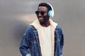 Portrait stylish urban smiling african man in headphones enjoying listening to music on gray metal wall background Royalty Free Stock Photo