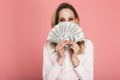 Portrait of stylish woman hiding while holding money fan isolated over pink background Royalty Free Stock Photo