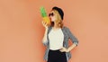 Portrait of stylish woman kissing pineapple wearing a black hat, sunglasses, striped shirt Royalty Free Stock Photo