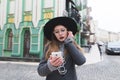 Portrait of a stylish woman listening to music in headphones on the backdrop of a beautiful old town. Royalty Free Stock Photo