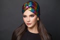 Portrait of stylish woman with long smooth straight hair and makeup in turban hat on black background