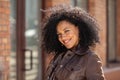 Portrait of stylish young African American woman flirtatious smiling and looking at camera. Brunette in brown leather