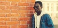 Portrait of stylish young african man model looking away on city street over brick wall background Royalty Free Stock Photo