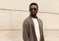 Portrait stylish young african man model looking away wearing a knitted cardigan isolated on a city street background Royalty Free Stock Photo