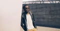 Portrait of stylish young african man model posing wearing black rock leather jacket with bag on city street background Royalty Free Stock Photo