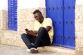 Stylish young african man sitting outside and using mobile phone Royalty Free Stock Photo