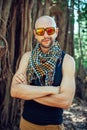 Portrait of stylish young bald guy in sunglasses on blurry background outdoor. Attractive cheerful man poses for the camera and