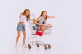 Portrait of stylish young girls going shopping together. Girl sitting on shopping trolley. Giant sales Royalty Free Stock Photo