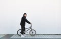 Portrait of a stylish young man with a bmx bike on the background of a white wall Royalty Free Stock Photo