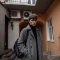 Portrait of a stylish young man with a handsome serious face with a trendy hairstyle in a gray checkered elegant coat with a Royalty Free Stock Photo