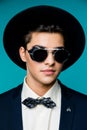 Portrait of a stylish young man in hat wearing elegant suit and sunglasses. Royalty Free Stock Photo