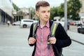 Portrait of stylish young man in plaid shirt and jacket with backpack walking in the city outdoors. Student travel. Royalty Free Stock Photo