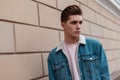 Portrait stylish young man in trendy blue youth casual jeans clothes near vintage wall outdoors in city. European guy in trendy Royalty Free Stock Photo