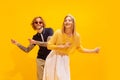 Portrait of stylish young man and woman dancing, posing isolated over yellow studio background. Looks happy and Royalty Free Stock Photo