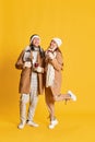 Portrait of stylish young man and woman, smiling coupe in winter clothes walking, drinking mulled wine isolated over Royalty Free Stock Photo