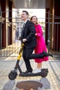 Portrait of stylish young people riding electric scooter in city street and smiling Royalty Free Stock Photo