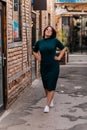 Portrait of stylish young pretty hipster woman in sunglasses and green dress, vintage urban background, street photo brick wall, Royalty Free Stock Photo