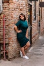 Portrait of stylish young pretty hipster woman in sunglasses and green dress, vintage urban background, street photo brick wall, Royalty Free Stock Photo