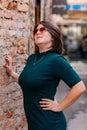 Portrait of stylish young pretty hipster woman in sunglasses and green dress, vintage urban background, street photo brick wall, Royalty Free Stock Photo