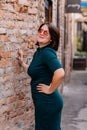 Portrait of stylish young pretty hipster woman in sunglasses and green dress, vintage urban background, street photo, brick wall, Royalty Free Stock Photo