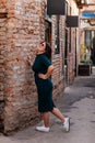 Portrait of stylish young pretty hipster woman in sunglasses and green dress, vintage urban background, street photo brick wall, Royalty Free Stock Photo