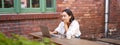 Portrait of stylish young woman, brunette girl with laptop, sitting outdoors and using computer Royalty Free Stock Photo