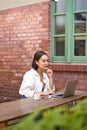 Portrait of stylish young woman, brunette girl with laptop, sitting outdoors and using computer Royalty Free Stock Photo