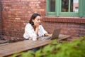 Portrait of stylish young woman, brunette girl with laptop, sitting outdoors and using computer Royalty Free Stock Photo