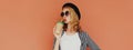 Portrait stylish young woman drinking coffee or juice wearing a striped black white shirt, hat, sunglasses on brown background Royalty Free Stock Photo