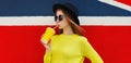 Portrait of stylish young woman drinking juice wearing a yellow sweater, round hat over colorful background Royalty Free Stock Photo