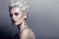 Profile of gorgeous young model with gray hairstyle, naked shoulders, makeup, smokey eyes, isolated on grey background.