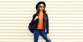 Portrait of stylish young woman model wearing black round hat, leather jacket, sunglasses on white background Royalty Free Stock Photo