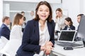 Succesful smiling young businesswoman foreground in office