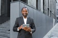 Portrait of a successful African American boss, a businessman in a suit smiling and looking at the camera, a man holding