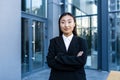 Portrait of successful asian business woman with crossed arms smiling and looking at camera, outside office center Royalty Free Stock Photo