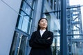 Portrait of successful asian business woman with crossed arms smiling and looking at camera, outside office center Royalty Free Stock Photo