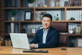 Portrait of a successful Asian businessman, man working in the office sitting at the table, looking at the camera and smiling, Royalty Free Stock Photo