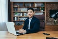 Portrait of a successful Asian businessman, man working in the office sitting at the table, looking at the camera and smiling, Royalty Free Stock Photo