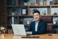 Portrait of a successful Asian businessman, man working in the office sitting at the table, looking at the camera and smiling, Royalty Free Stock Photo