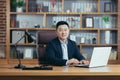 Portrait of a successful Asian businessman, man working in the office sitting at the table, looking at the camera and smiling, Royalty Free Stock Photo