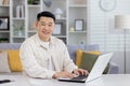 Portrait of successful Asian programmer, man working remotely from home office, businessman smiling and looking at Royalty Free Stock Photo