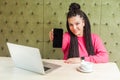 Portrait of successful beautiful young woman with black dreadlocks in pink blouse is sitting, holding phone empty screen and Royalty Free Stock Photo