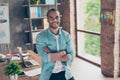 Portrait of successful black guy, looking at the camera, standing with crossed arms at his work place in the office, in casual sma Royalty Free Stock Photo