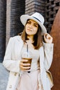 Portrait of successful business woman holding cup of cold drink in hand on her way to work on city street Royalty Free Stock Photo