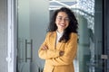 Portrait of successful business woman inside office, latin american boss in yellow suit smiling and looking at camera Royalty Free Stock Photo