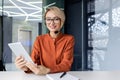 Portrait of successful business woman office worker, blonde smiling and looking at camera holding tablet computer in Royalty Free Stock Photo