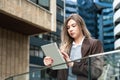 Portrait of a successful business woman using digital tablet in front of modern business office building. Professional female, Royalty Free Stock Photo