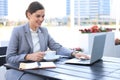 Portrait of successful business woman using laptop and smiling while sitting in cafe, outdoor Royalty Free Stock Photo