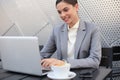 Portrait of successful business woman using laptop and smiling while sitting in cafe, outdoor Royalty Free Stock Photo